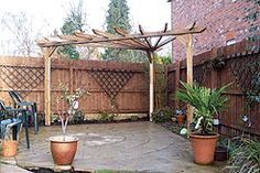 an outdoor patio with potted plants on the ground and a pergolated area