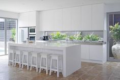 a large kitchen with white cabinets and counter tops next to a sliding glass door that leads to an outside patio