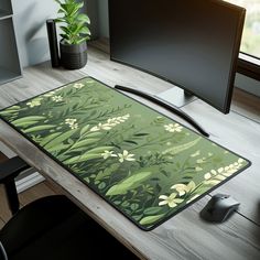 a computer desk with a monitor, keyboard and mouse pad on it in front of a window