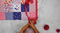 a woman is making a quilt on the wall next to some scissors and other crafting supplies