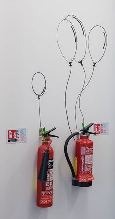 two red fire extinguishers are attached to the wall with balloons on them