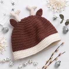 a brown and white crocheted hat sitting on top of a table next to flowers