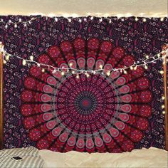 a large red and black tapestry hanging on the wall next to a bed with pillows