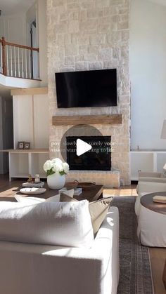 a living room filled with white furniture and a flat screen tv mounted above a fireplace