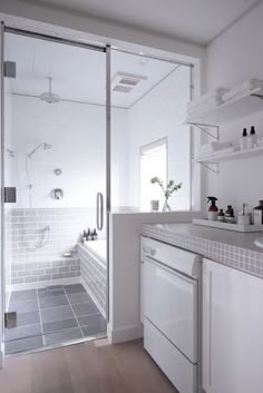 a white tiled bathroom with glass shower door and tile flooring, along with built - in shelving