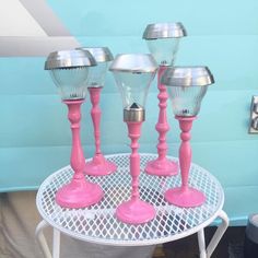 four pink goblets sitting on top of a white table next to a blue wall