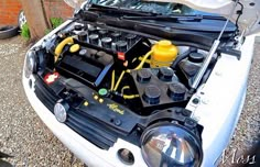 the engine compartment of a white car with yellow and black wires attached to it's hood