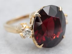 "This ring features a simple and classically designed mounting, the structural openwork shoulders lend a sense of light and grace to the mounting. Cut into a classic oval cut, the deep red cherry garnet in the center adds a lovely pop of color and also an interesting shape to a simple ring! Twinkling diamonds on either side of the stone add an extra bit of sparkle. Metal: 14K Yellow Gold Gem: Garnet 10.14 Carats Gem Measurements: 12.5 x 13.7 mm, Oval Accents: 2 Diamonds totaling .20 Carats, G in Luxury Garnet Rings With Accent Stones, Elegant Multi-stone Garnet Rings, Gold Garnet Multi-stone Ring, Yellow Gold Garnet Multi-stone Ring, Diamond Ring Yellow Gold, Gold Garnet Ring, Pyrope Garnet, Garnet Rings With Polished Finish - Fine Jewelry, Garnet And Diamond Ring