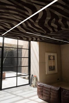 a living room filled with furniture next to a sliding glass door covered in zebra print