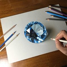 a blue diamond surrounded by colored pencils on top of a piece of white paper