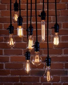 a bunch of light bulbs hanging from a brick wall