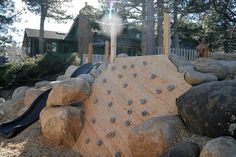 an outdoor play area with rocks and a slide