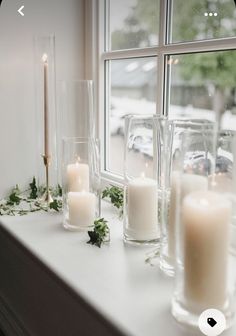 candles are lined up on a window sill