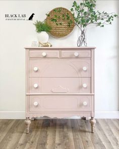 a pink dresser sitting on top of a hard wood floor next to a white wall