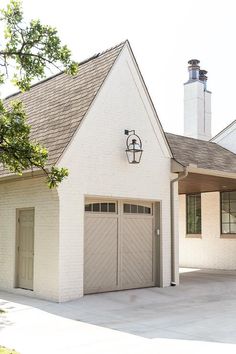 a white house with two garages and a chimney