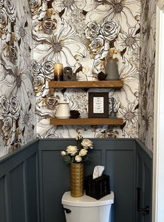 a white toilet sitting in a bathroom next to a wall mounted shelf with flowers on it