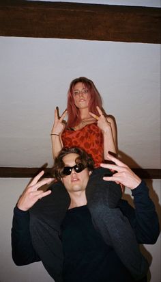 two people are posing for the camera with their hands in the air and one person is wearing sunglasses