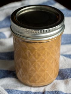 a glass jar filled with peanut butter sitting on top of a blue and white towel