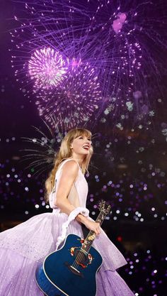 taylor swift performs on stage with her guitar and fireworks in the background