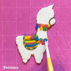 a cookie shaped like a llama and a toothbrush on a pink tile background