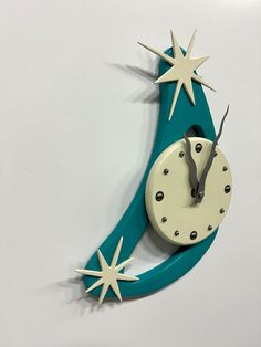 a clock that is on the wall and has stars attached to it, as well as an arrow