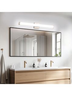 a bathroom with a large mirror above the sink and two vases on the counter