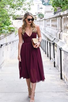 a woman is walking down the sidewalk wearing a dress and heels with her hand in her pocket