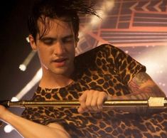 a man in leopard print shirt holding a large metal object with his arm and hand