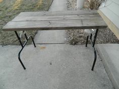 a wooden table sitting on top of a sidewalk