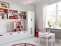 a child's room with white furniture and pink accessories on the shelves, along with a large window