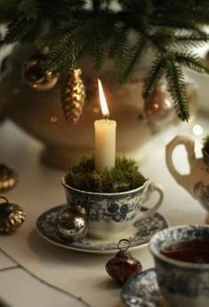 a table topped with cups and saucers filled with teacups next to a christmas tree