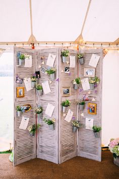 a room divider with several plants and pictures on the sides, hanging from it's sides