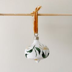 an ornament hanging from a clothes line on a hanger with leaves painted on it