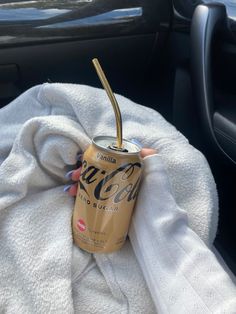 a woman holding up a can of coca - cola in her hand while sitting in a car