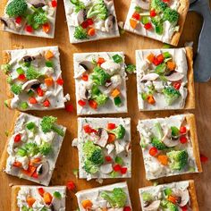 several square pieces of bread with different vegetables on them next to a knife and fork