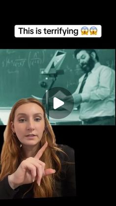 a woman is pointing at the camera with her finger in front of a blackboard