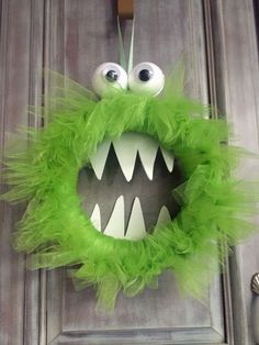 a green wreath with googly eyes and mouthy hair hanging on the front door