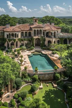 an aerial view of a large mansion with a pool in the foreground and trees surrounding it