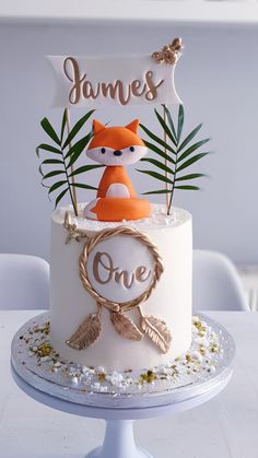 a white cake with an orange fox on top and one sign above it that says james