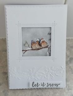 a card with two birds sitting on a tree branch in the snow and let it snow