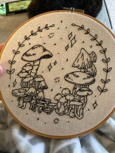 someone is holding up a embroidery project with mushrooms on it