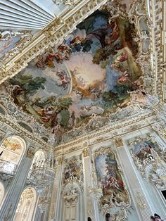 an ornate ceiling with paintings on it and people standing in the room next to it