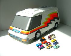 a toy bus with cars sitting on the floor next to it's back door