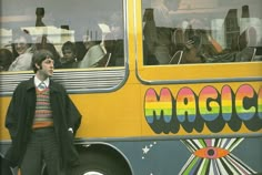 a man standing in front of a yellow bus