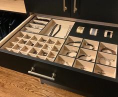 a drawer filled with lots of jewelry on top of a wooden table