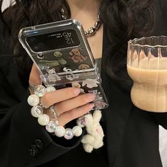 a woman is holding a cell phone in her hand and some beads around her wrist