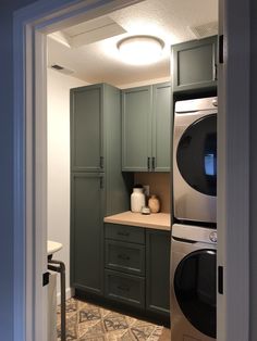 a kitchen with green cabinets and an oven in the corner, next to a washer and dryer