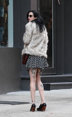 a woman with black and white hair is walking down the street