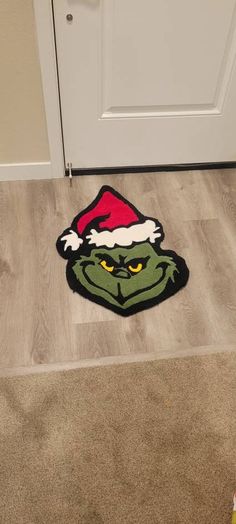 the grin face is on the floor in front of a door with santa's hat