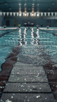 an empty swimming pool with no people or swimmers on the side and lights reflecting in the water